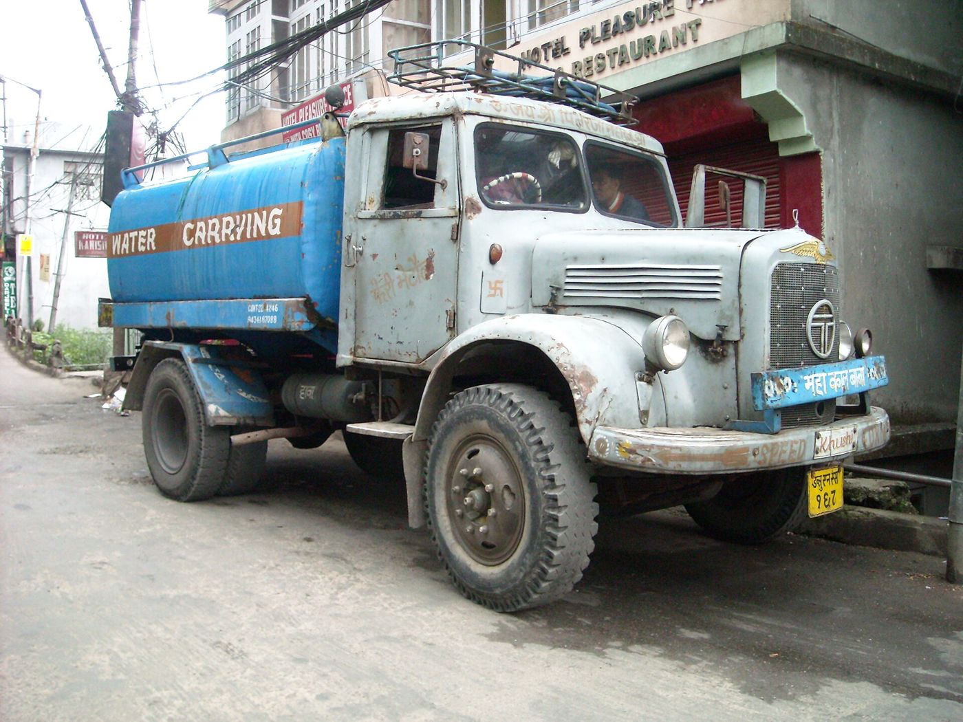 An old blue tanker truck marked Water Carrying parked on a street in Darjeeling