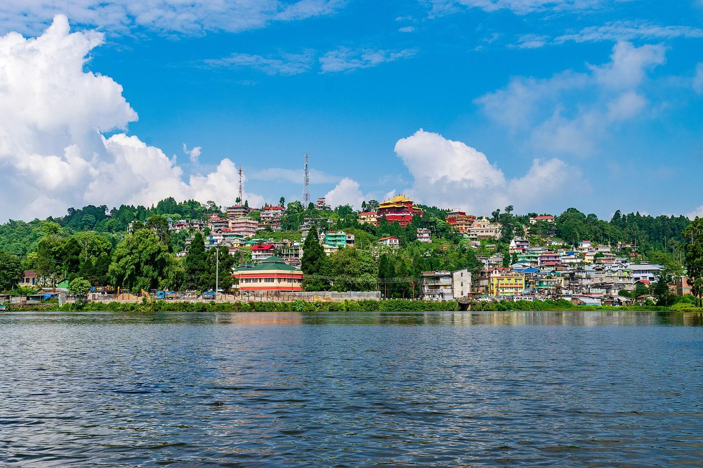 Sumendu Lake in Mirik with the town on the hillside behind it under a blue sky